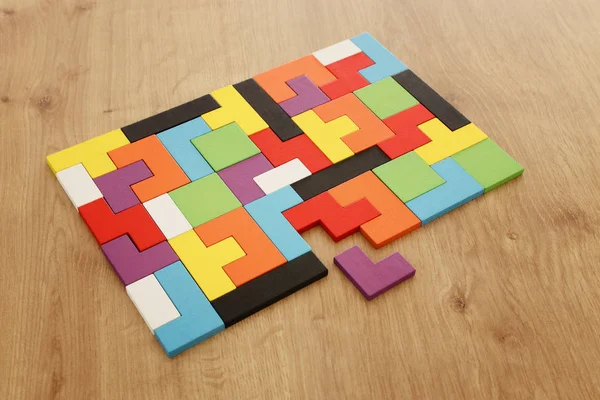 Un puzzle carré coloré tangram, sur une table en bois — Photo