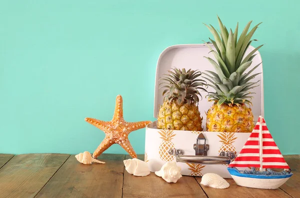 Pareja madura de piña en maleta sobre mesa de madera o cubierta. Concepto de vacaciones de verano tropical — Foto de Stock