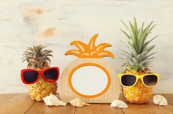 Пустая фоторамка и пара забавных ананасов в солнечных очках. Для фотографии и монтажа альбомов — стоковое фото