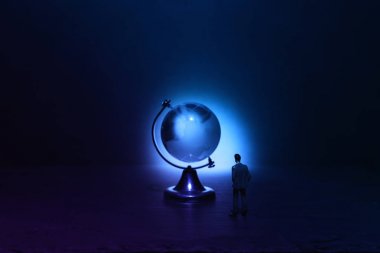 Minyatür adam karanlık ve dramatik ışık.küresel sorunlar kavramı önünde Küçük kristal küre bakıyor