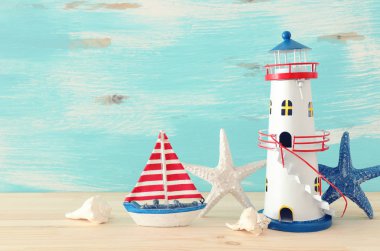 pastel mavi arka plan ahşap masa veya raf üzerinde vintage tekne, denizyıldızı, deniz feneri ve deniz kabukları ile tatil ve yaz konsepti