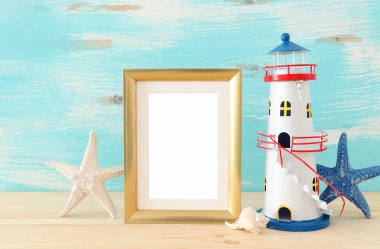 Boş fotoğraf çerçevesi ve ahşap masa üzerinde deniz feneri ile deniz kavramı. Fotoğraf montajı için