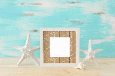 Ahşap masa üzerinde boş fotoğraf çerçevesi ve denizyıldızı ile deniz konsepti. Fotoğraf montajı için