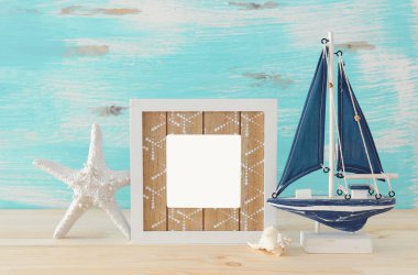 Ahşap masa üzerinde boş fotoğraf çerçevesi ve yelken teknesi ile deniz kavramı. Fotoğraf montajı için