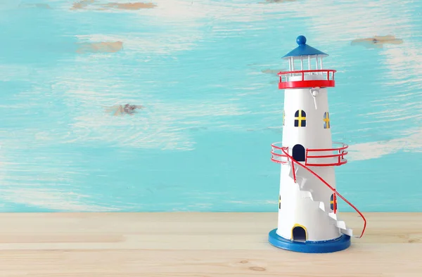 Ahşap masa veya raf pastel mavi arka plan önünde vintage deniz feneri ile tatil ve yaz konsepti — Stok fotoğraf
