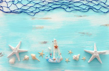 antika tekne, fishnet, yıldız balığı ve pastel mavi ahşap arka plan üzerinde deniz kabukları ile tatil ve yaz konsepti. Üst görünüm düz yatıyordu
