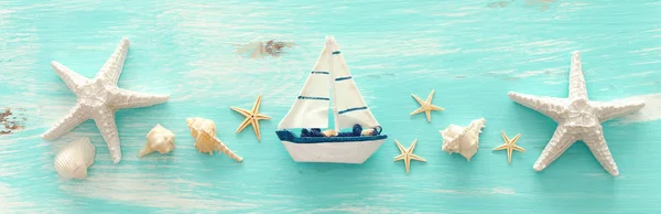 パステルブルーの木製の背景の上にヴィンテージボート、ヒトデや貝殻と休暇と夏のコンセプト。トップビューフラットレイ — ストック写真