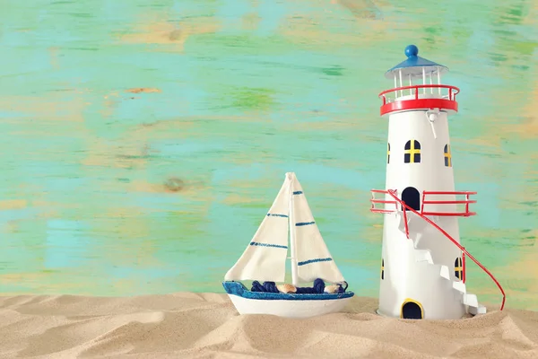 Vacances et concept d'été avec bateau vintage, étoile de mer, phare et coquillages sur la plage de sable devant fond vert pastel — Photo