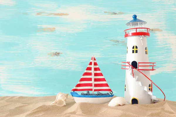 Vacances et concept d'été avec bateau vintage, étoile de mer, phare et coquillages sur la plage de sable devant fond bleu pastel — Photo