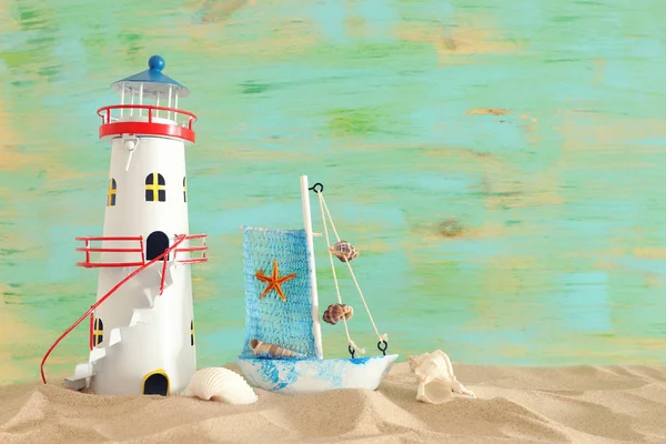 파스텔 그린 배경의 해변 모래 위에 빈티지 보트, 불가사리, 등대와 조개와 휴가와 여름 개념 — 스톡 사진