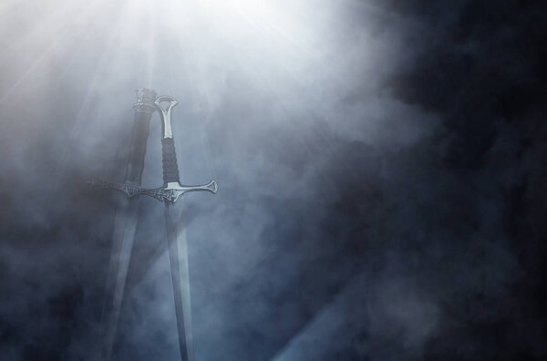 Mysterious and magical photo of silver sword over gothic black background with smoke. Medieval period concept