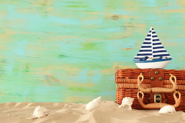 Valigia di paglia da spiaggia e barca di legno nella sabbia. Concetto di vacanza estiva tropicale — Foto Stock