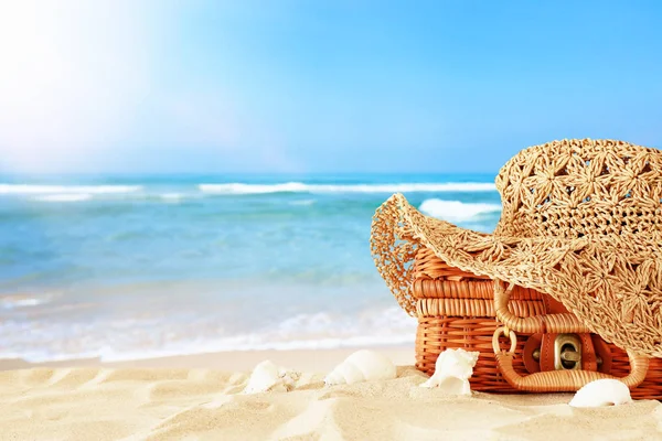 Beach fashion female hat over straw suitcase in the sand. Tropic — Stock Photo, Image