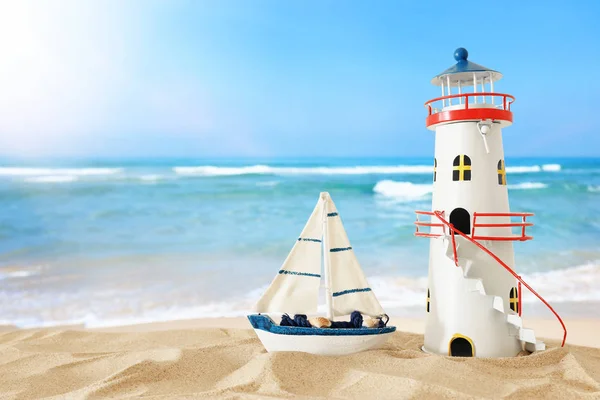 Vintage wooden boat and lighthouse over beach sand and sea lands — Stock Photo, Image