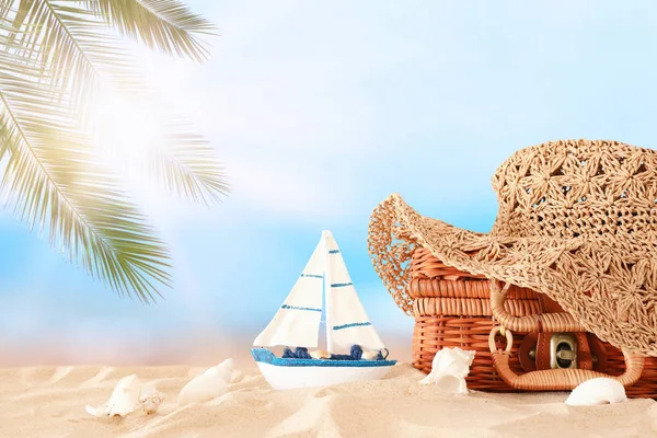 Cappello donna moda spiaggia sopra valigia di paglia nella sabbia. Concetto di vacanza estiva tropicale — Foto Stock