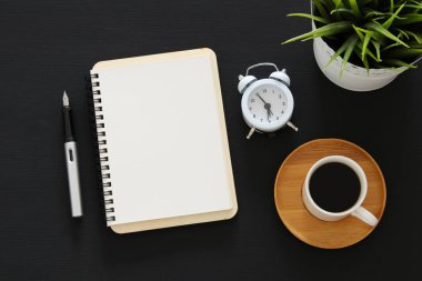 Siyah ofis masası masa üzerinde boş sayfalar ve diğer ofis malzemeleri ile dizüstü açık. Üstte görüntü