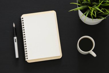 Siyah ofis masası masa üzerinde boş sayfalar ve diğer ofis malzemeleri ile dizüstü açık. Üstte görüntü