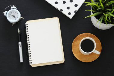 Siyah ofis masası masa üzerinde boş sayfalar ve diğer ofis malzemeleri ile dizüstü açık. Üstte görüntü