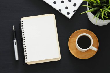 Siyah ofis masası masa üzerinde boş sayfalar ve diğer ofis malzemeleri ile dizüstü açık. Üstte görüntü