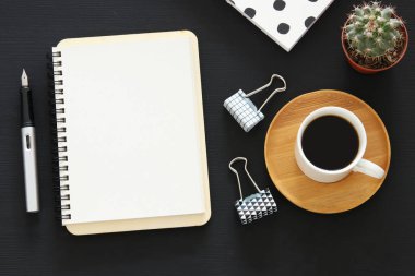 Siyah ofis masası masa üzerinde boş sayfalar ve diğer ofis malzemeleri ile dizüstü açık. Üstte görüntü