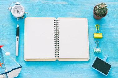 Mavi ofis masası üzerinde boş sayfalar ve diğer ofis malzemeleri ile defter açın. Üstte görüntü