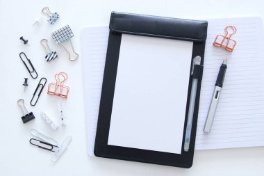 Not defteri, boş sayfalar ve diğer ofis malzemeleri olan beyaz ofis masası. Üst görünüm