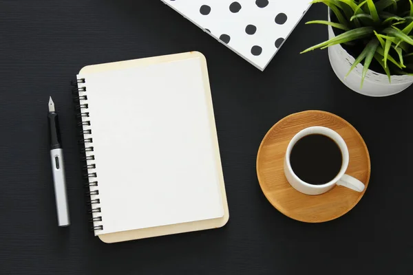 Abra o caderno com páginas vazias e outros materiais de escritório sobre mesa de escritório preto. Vista superior — Fotografia de Stock