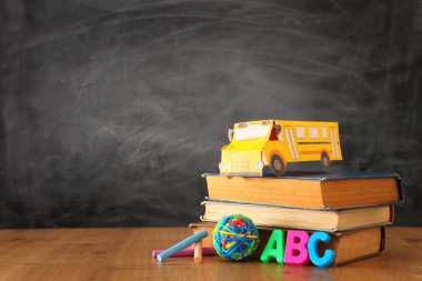 Okul konseptine geri dönelim. sınıf tahta önünde kitap üzerinde karton otobüs ve kalemler