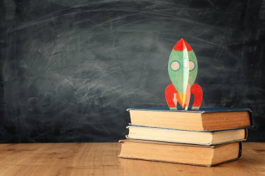 Okul konseptine geri dönelim. sınıf tahta önünde kitaplar üzerinde karton roket