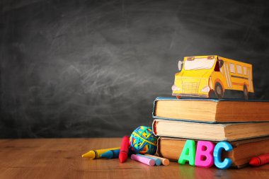 Okul konseptine geri dönelim. sınıf tahta önünde kitap üzerinde karton otobüs ve kalemler