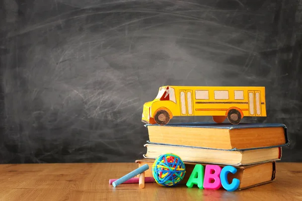De volta ao conceito de escola. ônibus de papelão e lápis sobre livros na frente da sala de aula quadro negro — Fotografia de Stock