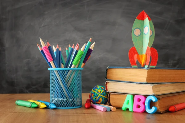 Вернемся к школьной концепции. картонная ракета и карандаши над книгами перед классной доской — стоковое фото