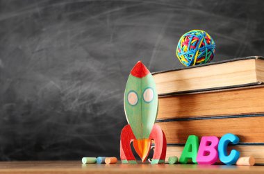 eğitim ve okul kavramına geri dön. sınıf kara tahta önünde karton roket, kitap ve tebeşir