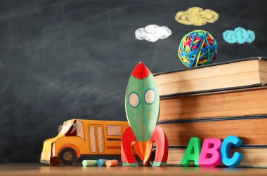 eğitim ve okul kavramına geri dön. sınıf kara tahta önünde karton roket, otobüs, kitap ve tebeşir