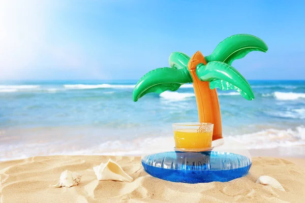 Vacaciones. concepto de vacaciones y verano con bebida de fruta fresca y piscina en forma de palma flotan sobre la arena en la playa — Foto de Stock