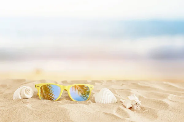 Töm sandstrand, snäckskal och solglasögon framför sommarse — Stockfoto