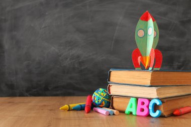 eğitim ve okul kavramına geri dön. sınıf kara tahta önünde karton roket, kitap ve tebeşir