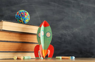 eğitim ve okul kavramına geri dön. sınıf kara tahta önünde karton roket, kitap ve tebeşir