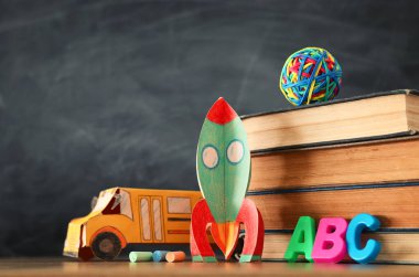 eğitim ve okul kavramına geri dön. sınıf kara tahta önünde karton roket, otobüs, kitap ve tebeşir