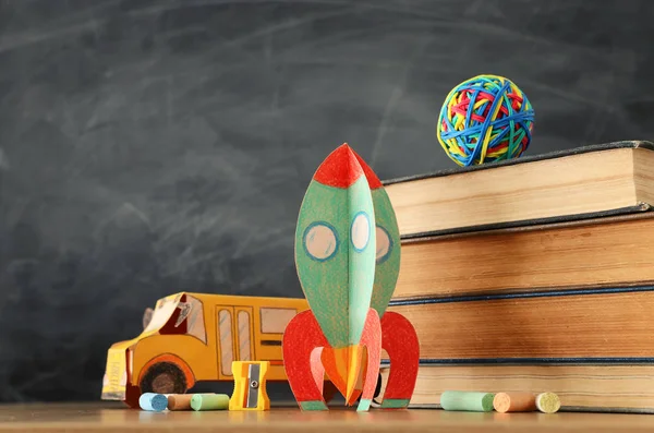 Образование и возврат к концепции школы. картонная ракета, автобус, книги и мел перед классной доской — стоковое фото
