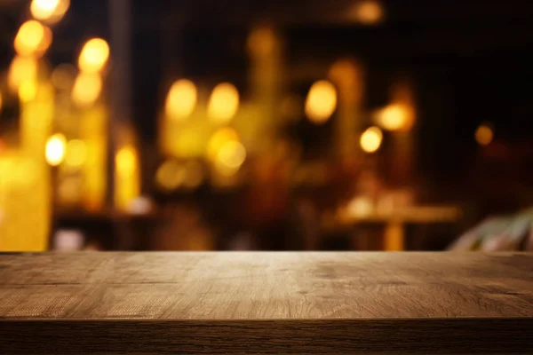 Fondo de la mesa de madera frente a las luces abstractas borrosas del restaurante — Foto de Stock