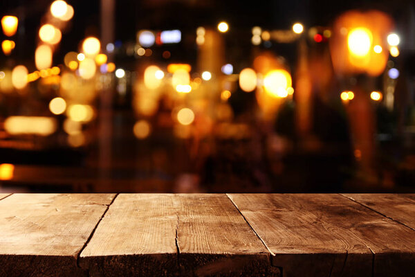background of wooden table in front of abstract blurred restaurant lights