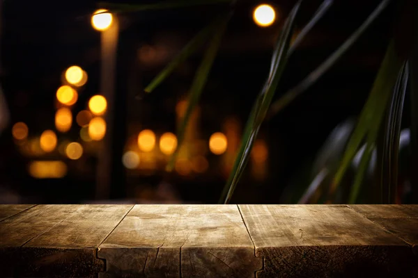 추상적 인 흐린 레스토랑 조명 앞에 나무 테이블의 배경 — 스톡 사진