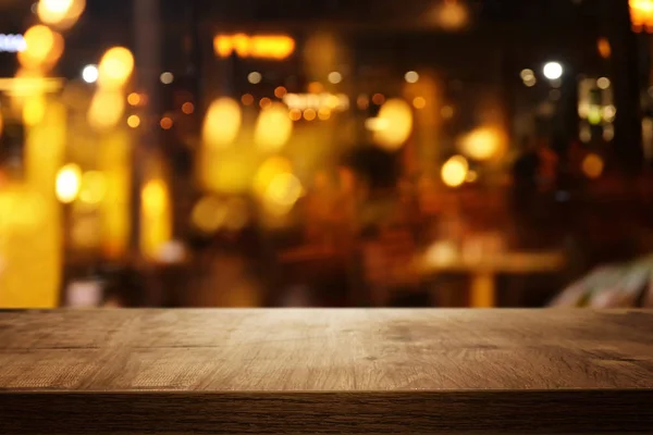 Fond de table en bois devant des lumières abstraites floues restaurant — Photo