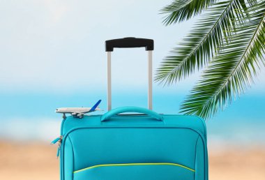 Tatil. seyahat konsepti. tropikal arka plan önünde mavi bavul ve uçak oyuncak