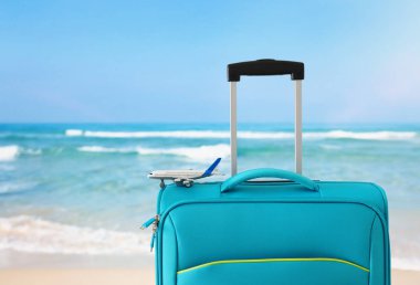 Tatil. seyahat konsepti. tropikal deniz arka plan mavi bavul ve uçak oyuncak infront