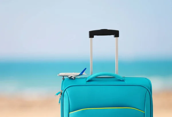 Vakantie. reis concept. blauwe koffer en vliegtuig speelgoed Infront van tropische zee achtergrond — Stockfoto