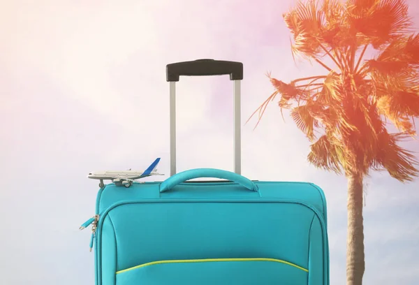 Vakantie. reis concept. blauwe koffer en vliegtuig speelgoed Infront van tropische achtergrond — Stockfoto