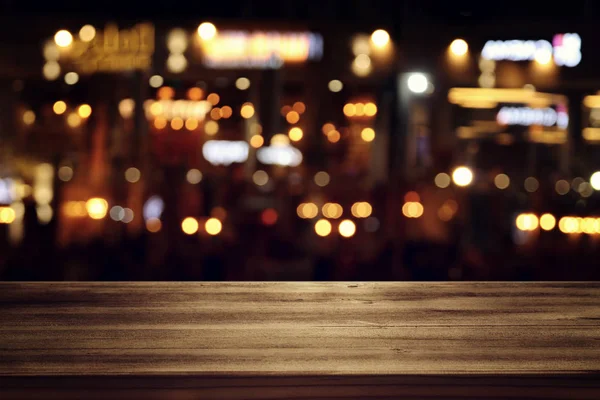 Background of wooden table in front of abstract blurred restaurant lights — Stock Photo, Image