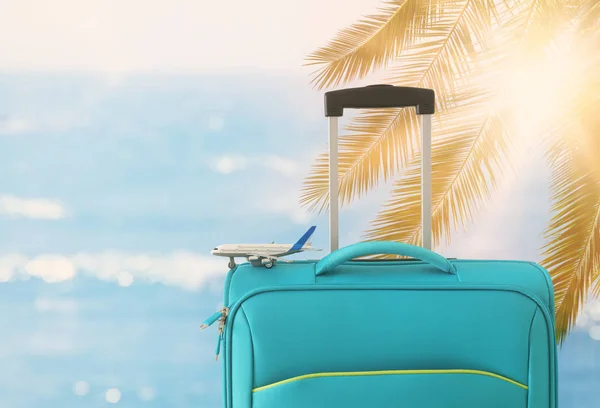 Dovolená. cestovní koncept. modrý kufr a cestovní hračka před tropickým pozadím — Stock fotografie